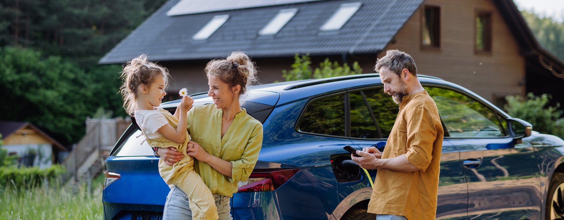 Familie mit Kind vor ihrem Elektroauto